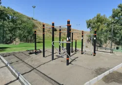 Parque de calistenia sobre suelo de arena en zona deportiva publica